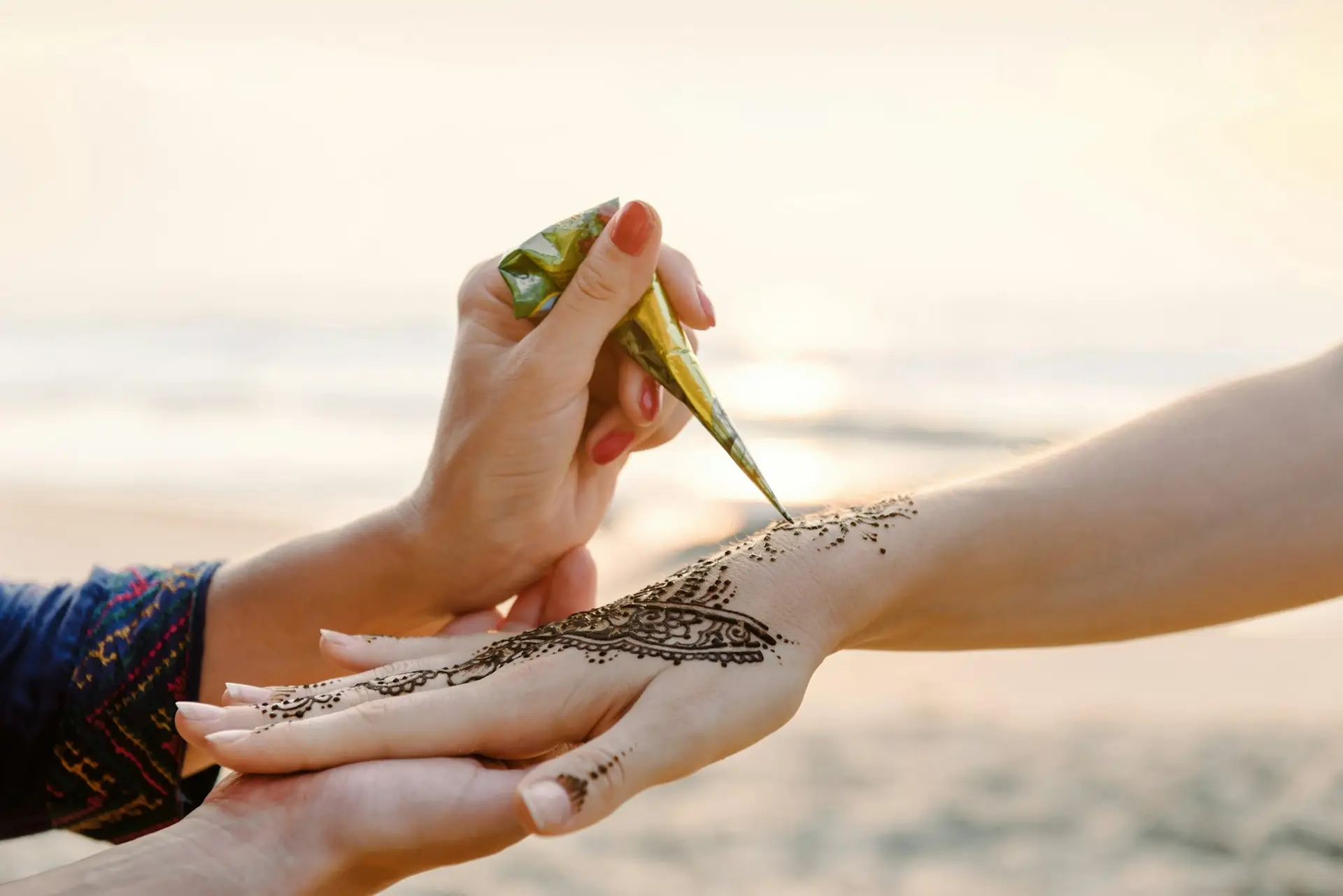Artist applying henna tattoo on women hands. Mehndi is traditional Indian decorative art. Close-up o