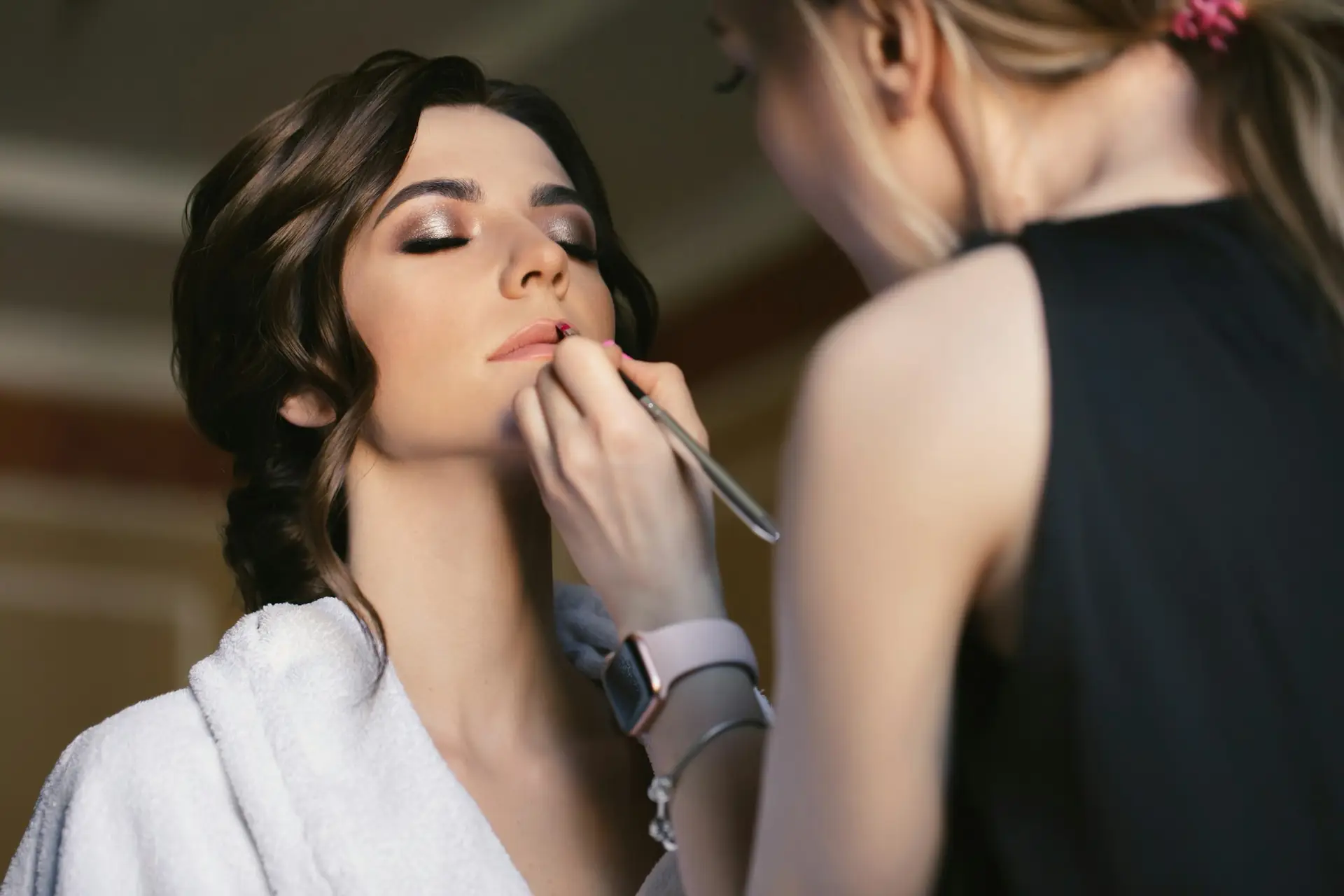 Make-up artist doing make up for young beautiful bride